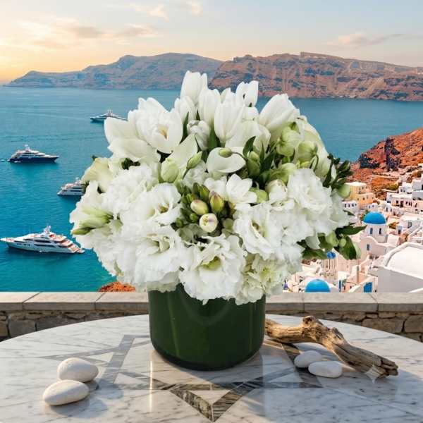 White floral arrangement in a dark green vase on a marble table