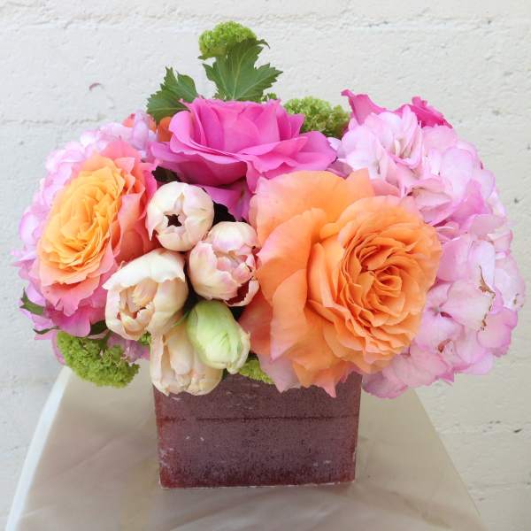 Pink and orange roses with hydrangeas in a square vase