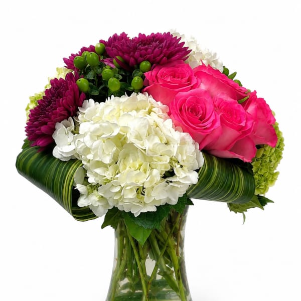 Bouquet of pink roses, white hydrangeas, and purple chrysanthemums in a glass vase