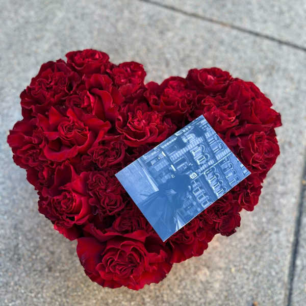 Heart-shaped bouquet of red roses with a small photo card on top