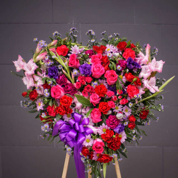 Heart-shaped floral spray with pink and red roses on an easel