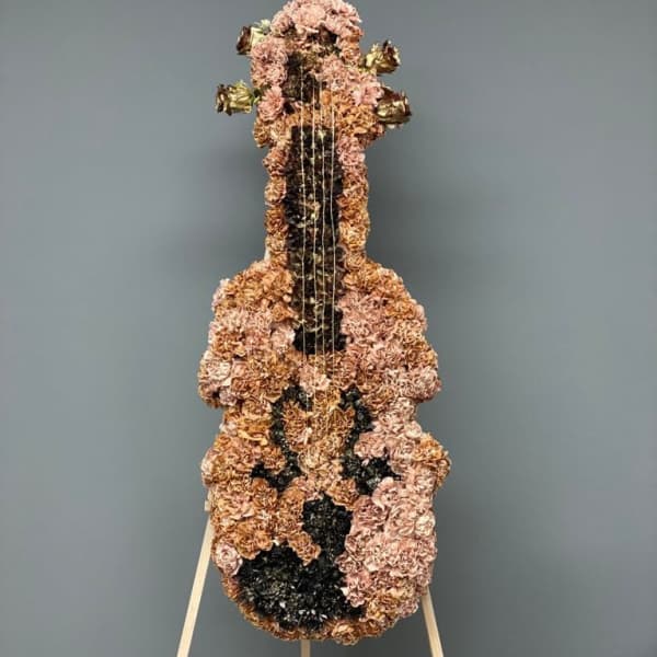 Floral arrangement shaped like a guitar on a stand