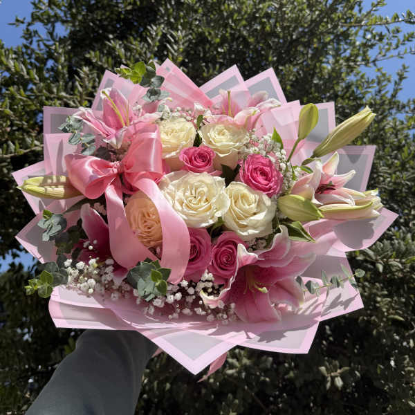 Pink and white bouquet of roses and lilies wrapped with a pink ribbon