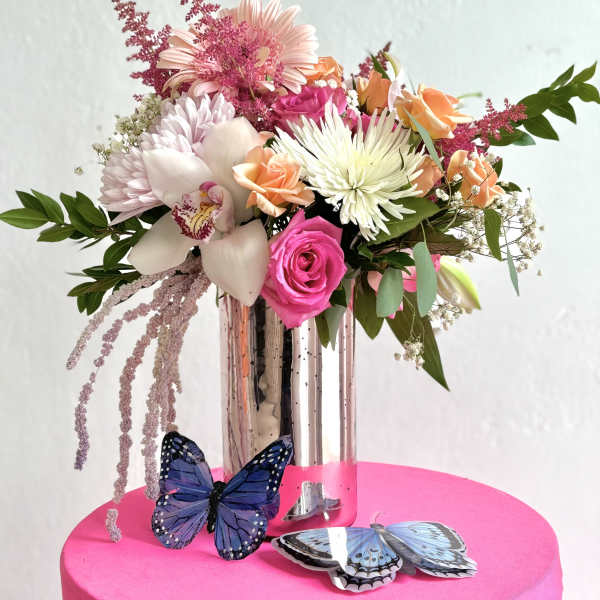 Mixed bouquet in a tall glass vase with butterflies at the base