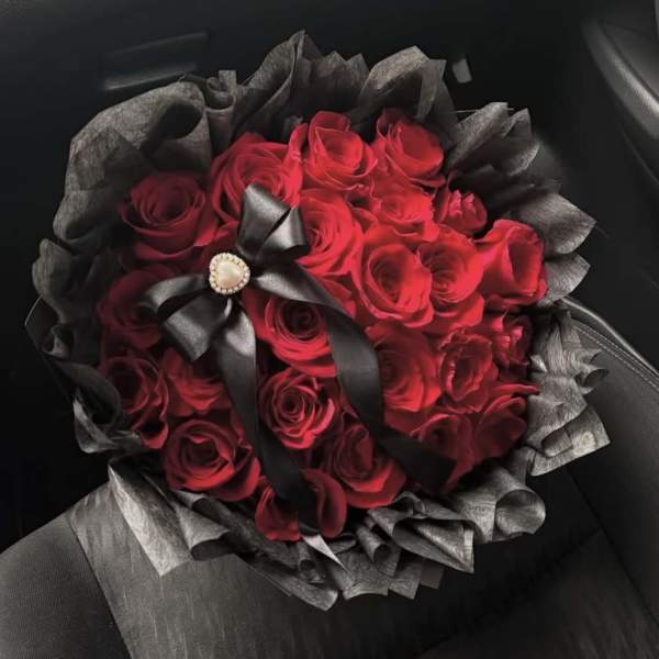 Bouquet of red roses wrapped in black paper with a black ribbon