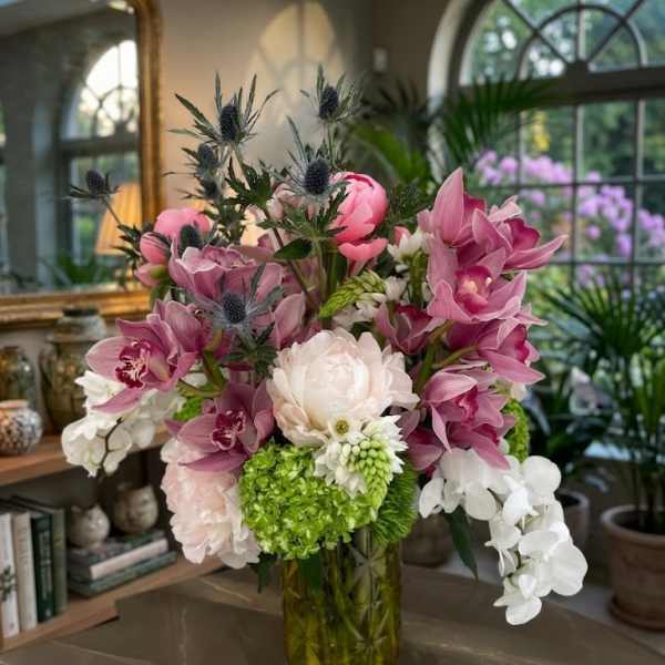 Pink and white orchid arrangement in a glass vase with green hydrangea