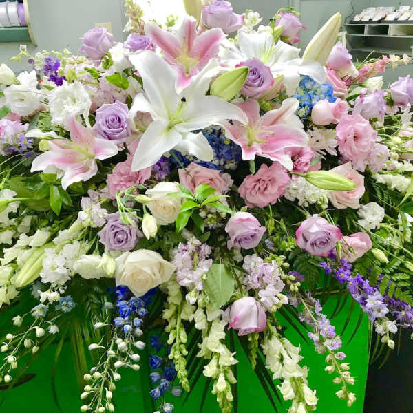 Large pastel floral arrangement with lilies, roses, and cascading blooms