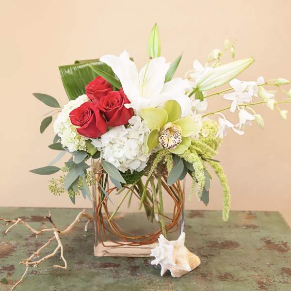 Bouquet of red roses, white lilies, and orchids in a glass vase