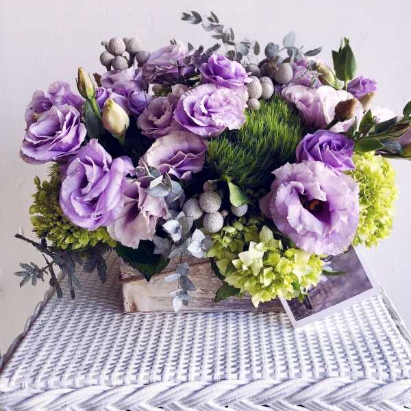 Purple lisianthus and green hydrangeas arranged in a low basket
