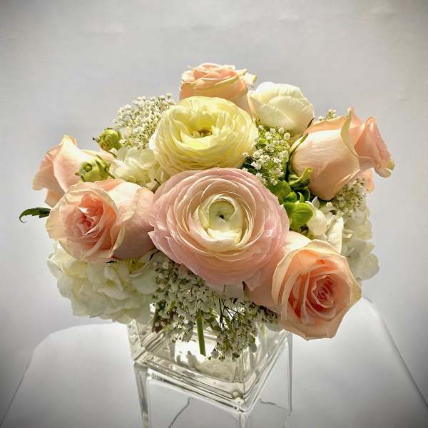Pastel roses and ranunculus arranged in a clear glass vase