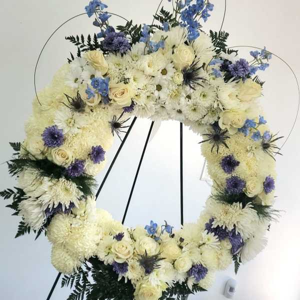 Large floral wreath of white and blue flowers on a black stand