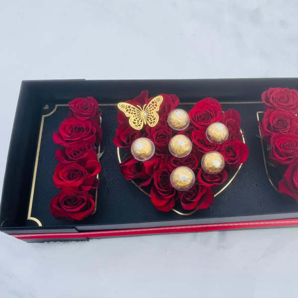 Black gift box with red roses, gold chocolates, and a butterfly decoration