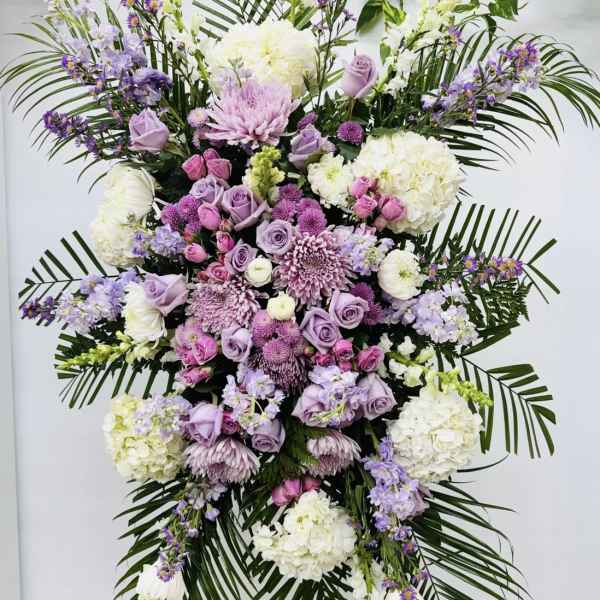 Large standing floral spray in lavender, pink, and white on a stand