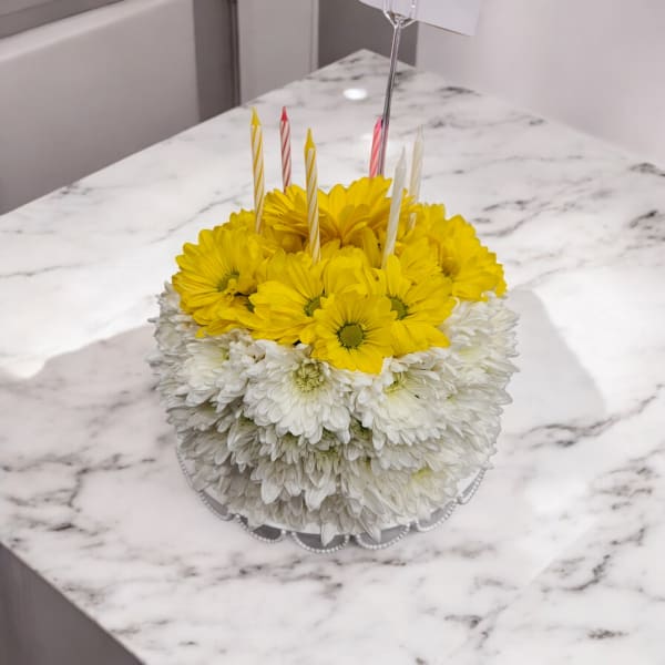 Round cake made of yellow and white daisies with birthday candles