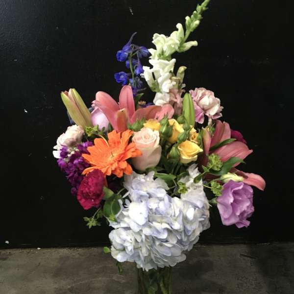 Mixed bouquet in a glass vase with lilies, roses, hydrangea, and snapdragons