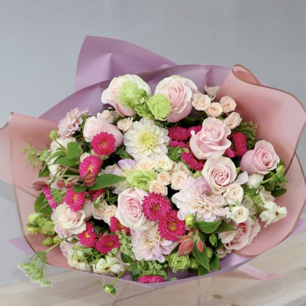 Bouquet of pink roses, white blooms, and bright pink flowers wrapped in pink paper