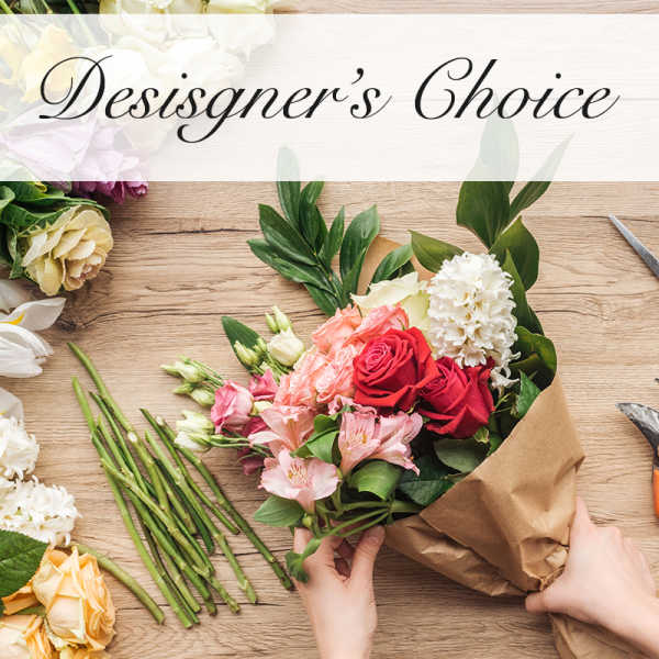 Hand-tied bouquet of red and pink roses with white blooms in brown paper