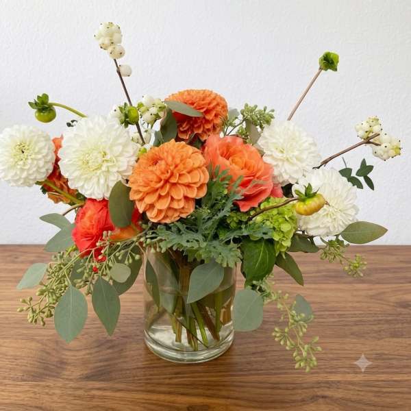 Orange and white flower arrangement in a clear glass vase