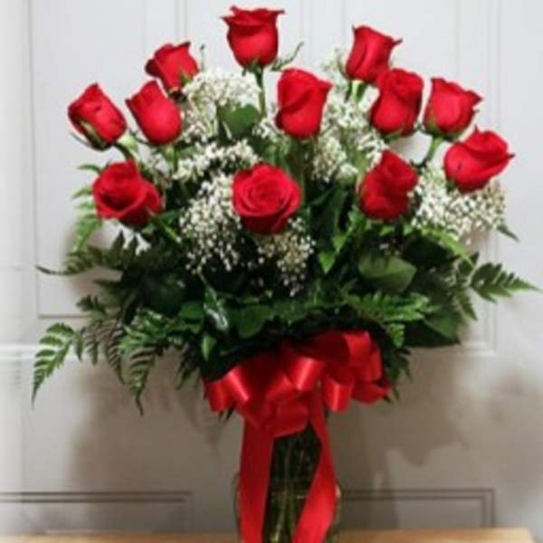 Bouquet of red roses with baby's breath in a glass vase tied with a red ribbon