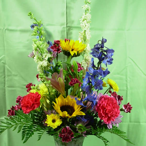 Mixed bouquet in a frosted glass vase with sunflowers and blue flowers