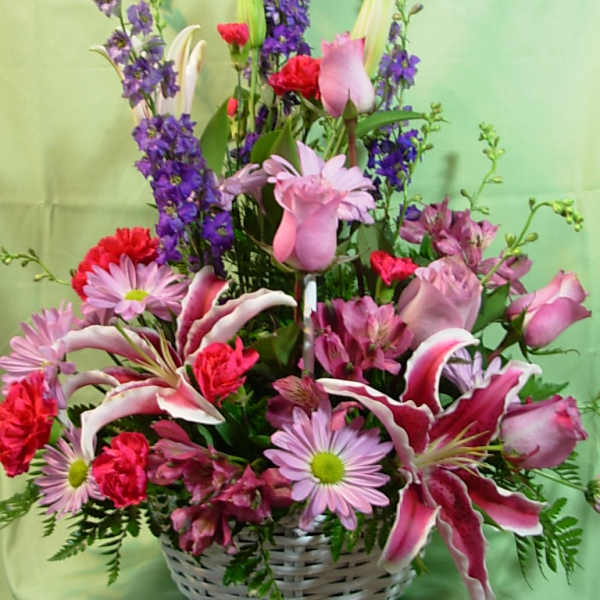 Mixed pink and purple flower arrangement in a white basket