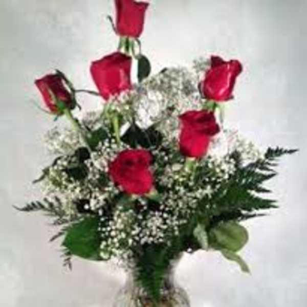 Red roses arranged in a clear glass vase with baby's breath