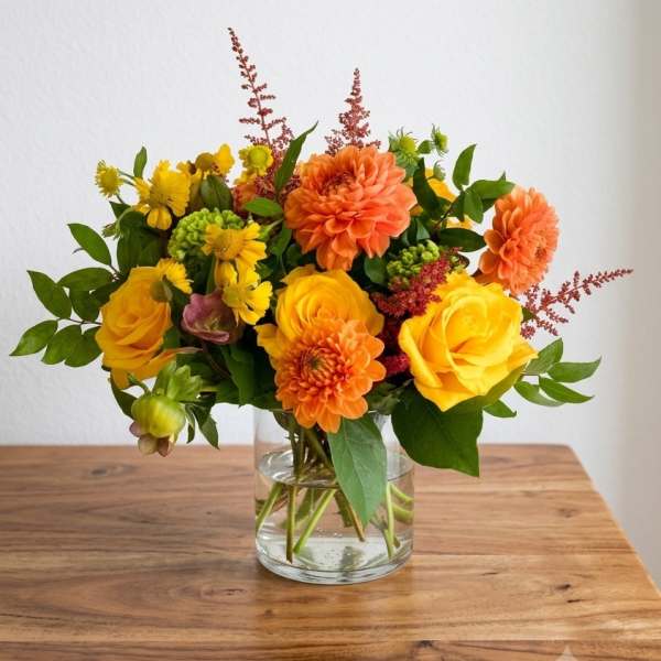 Yellow and orange flowers arranged in a clear glass vase