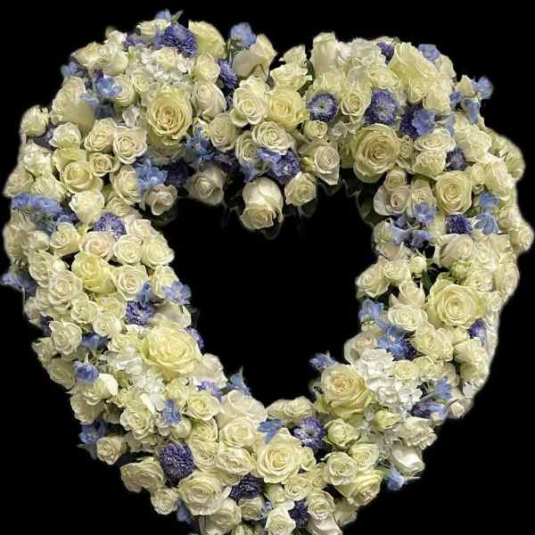Heart-shaped floral arrangement of white roses and blue flowers