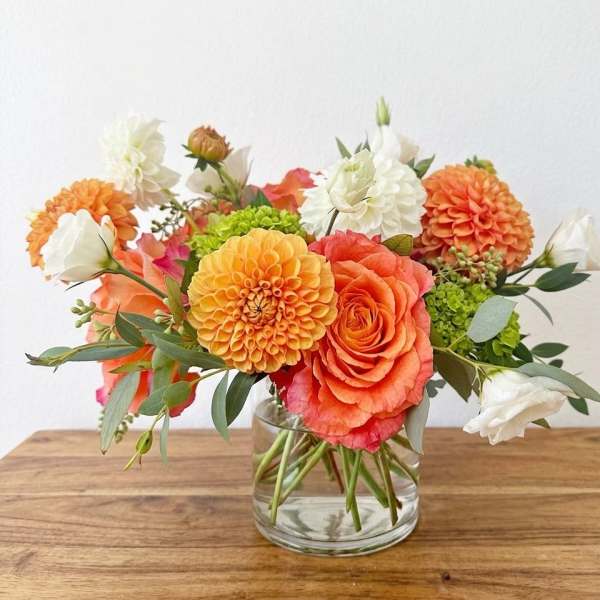 Orange and white flower arrangement in a clear glass vase