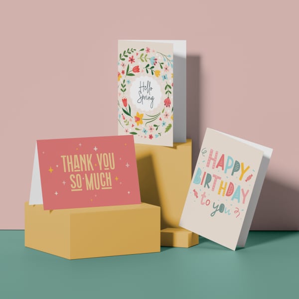 Three greeting cards on stacked boxes, including spring, thank you, and birthday designs.