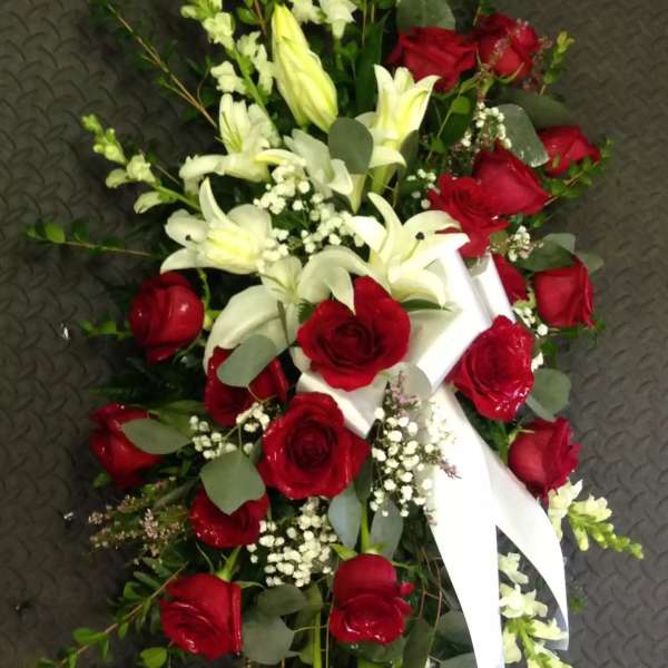 Red roses and white lilies arranged with a white ribbon