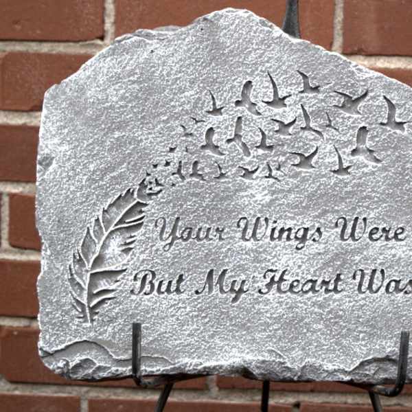 Engraved memorial stone with birds and a feather design