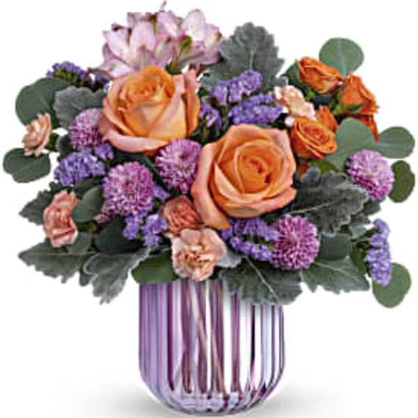 Orange roses and purple flowers in a striped glass vase