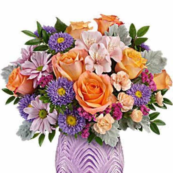 Mixed bouquet of orange roses and purple daisies in a purple vase