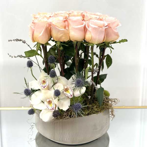 Pink roses and white orchids arranged in a round vase