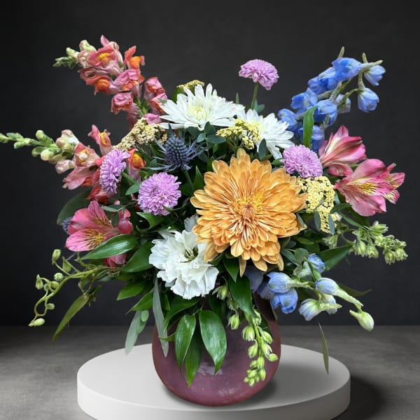 Colorful mixed flower arrangement in a round purple vase