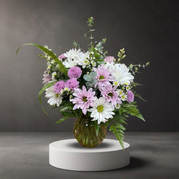 Pink and white daisy bouquet in a round glass vase