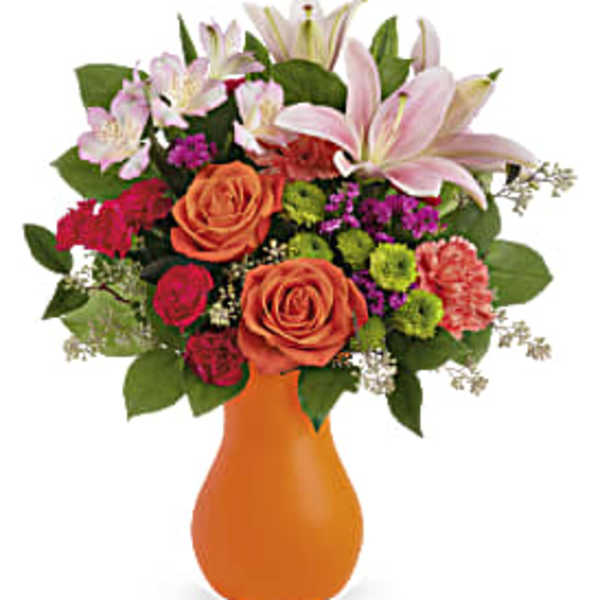 Mixed bouquet of pink lilies, roses, and carnations in an orange vase