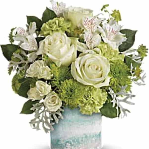 White roses and green flowers arranged in a glass vase