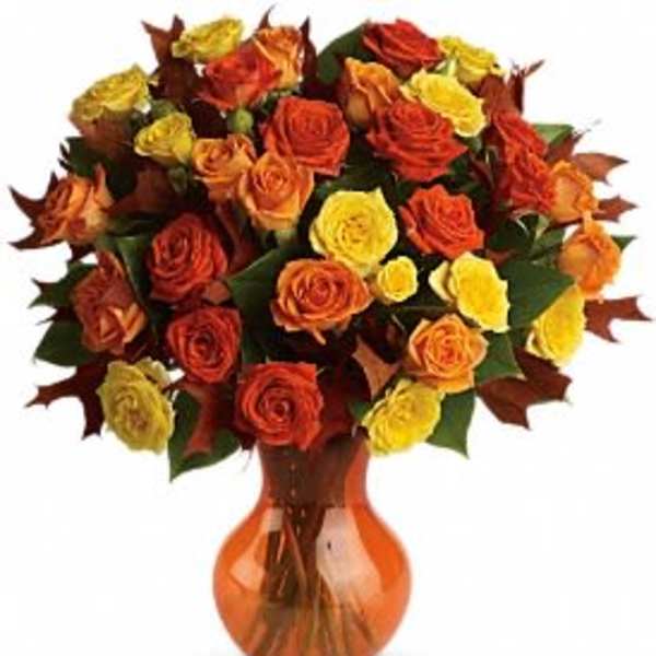 Bouquet of orange, red, and yellow roses in an amber vase