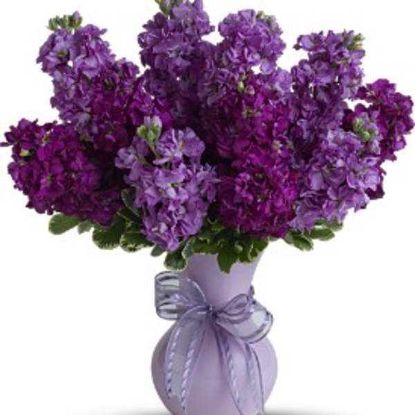Purple flower bouquet in a lavender vase with a ribbon bow
