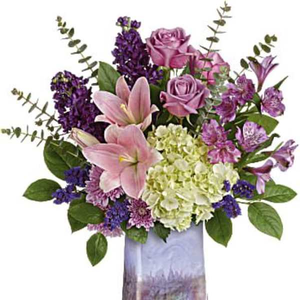 Bouquet of pink lilies, roses, and purple flowers in a tall vase