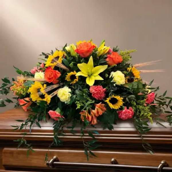 Colorful floral casket spray with lilies, roses, and sunflowers
