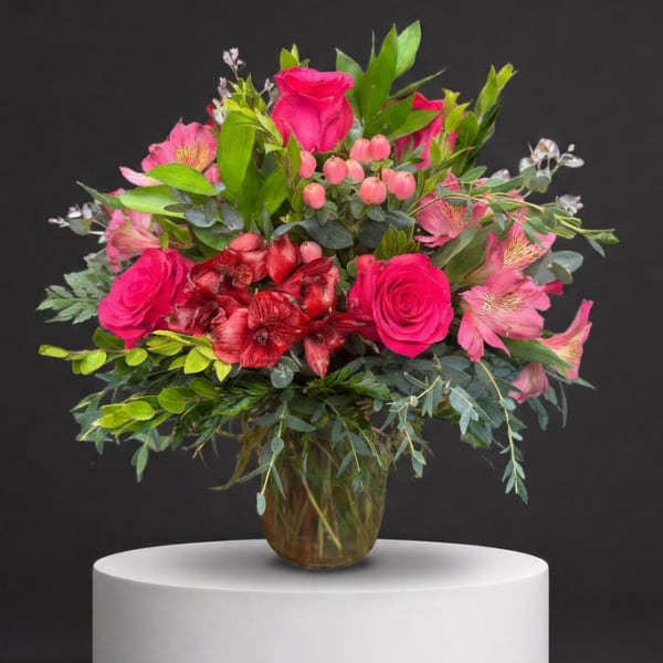 Pink roses and mixed blooms arranged in a glass vase