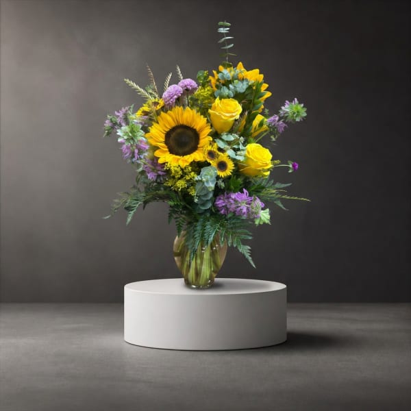Sunflower and yellow rose arrangement in a glass vase