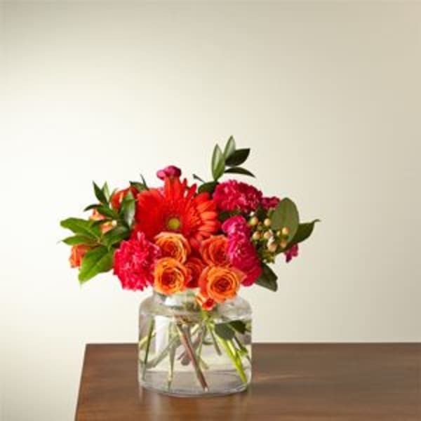 Orange and red flowers arranged in a clear glass vase