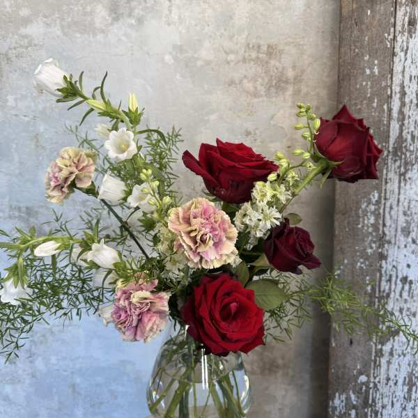 Bouquet of red roses and pink carnations in a clear glass vase