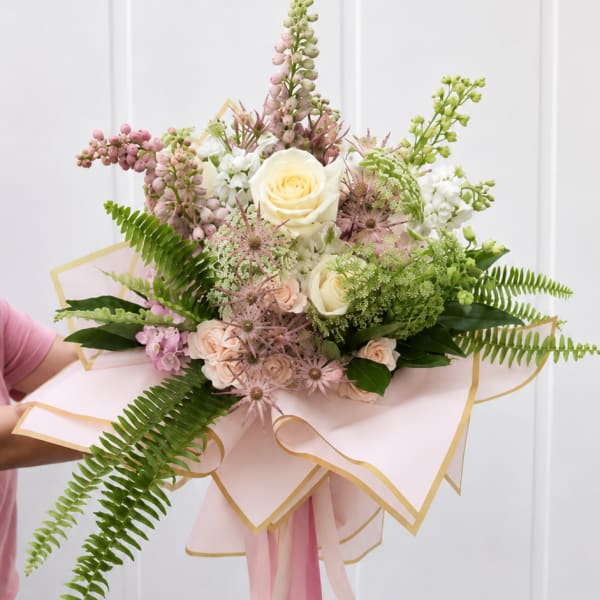 Hand-tied bouquet of cream and blush flowers with pink ribbon wrap