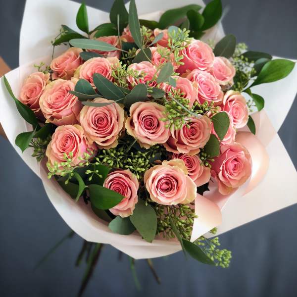 Bouquet of pink roses wrapped in white paper