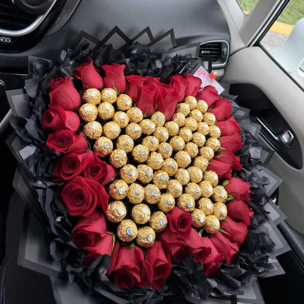 Heart-shaped bouquet of red roses and gold chocolates wrapped in black paper
